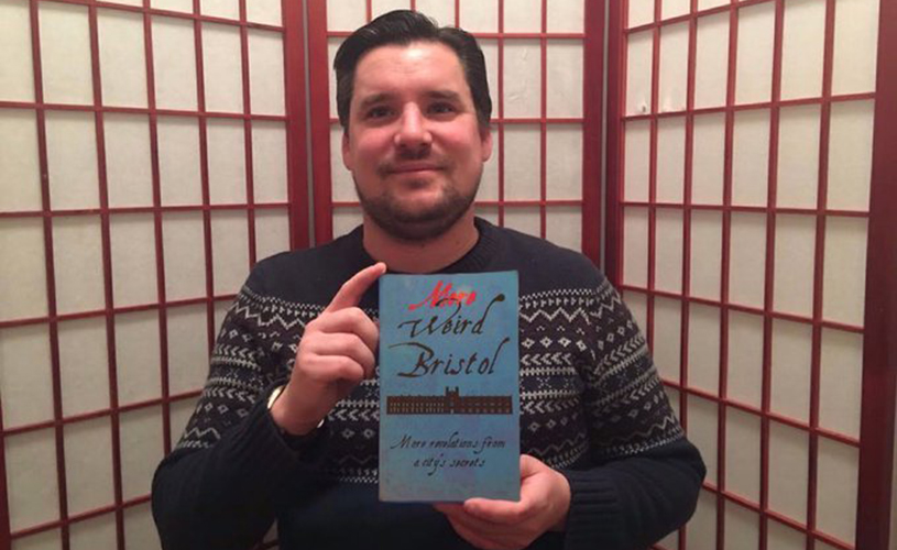 Author Charlie Revelle-Smith holding copy of More Weird Bristol
